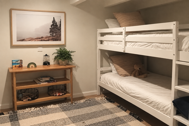Small bedroom with white bunk beds, wooden shelf, framed wall art, and a striped rug.