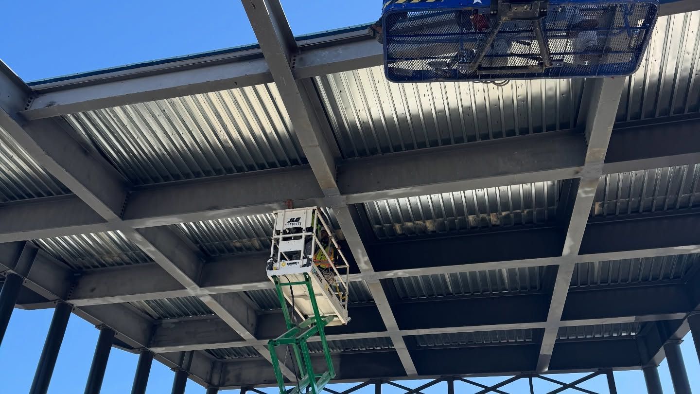 Underside of a metal roof with a hanging light fixture and blue sky visible above