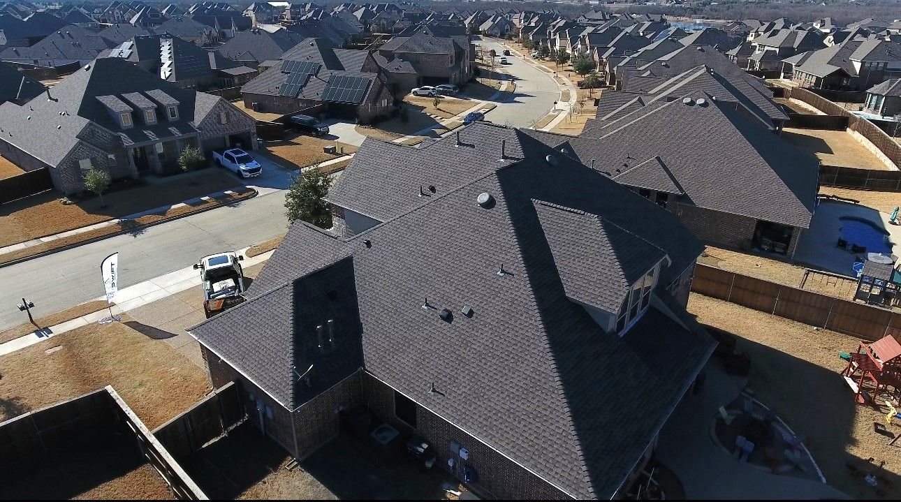 Aerial view of suburban houses with gray roofs.