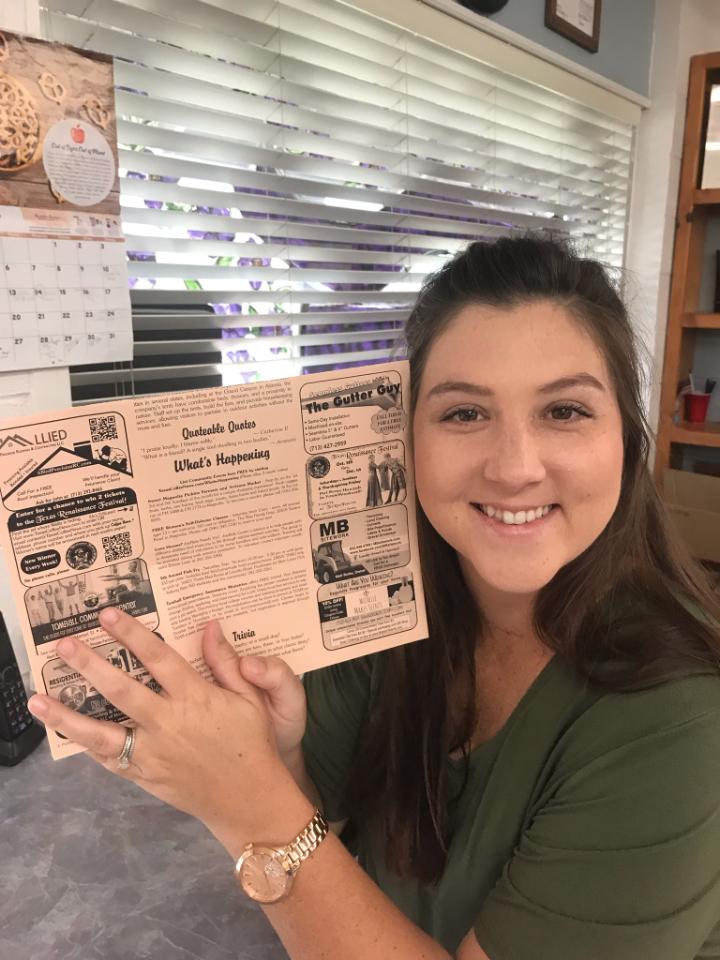 A woman is holding a magazine in her hands and smiling.
