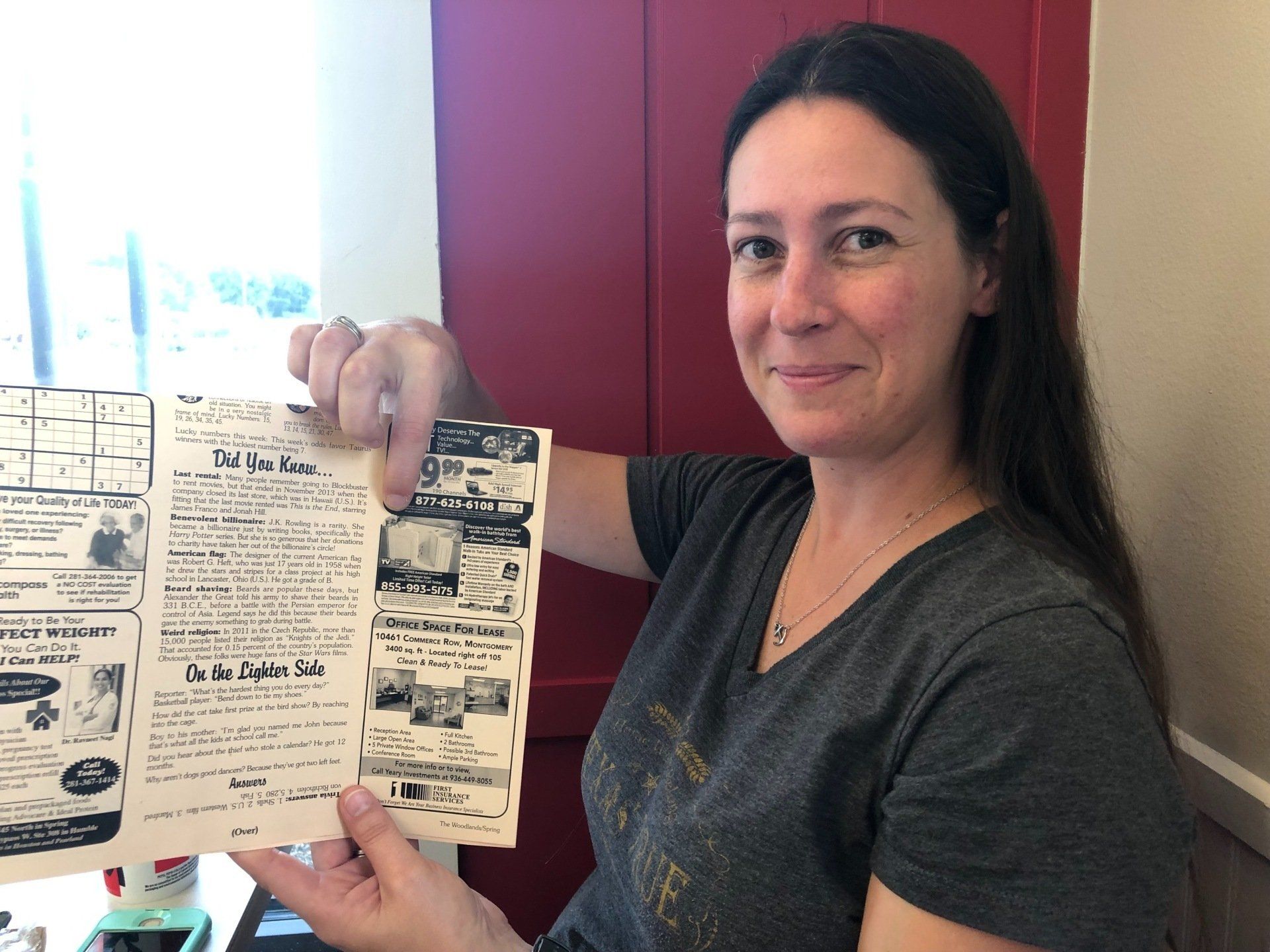A woman is holding a piece of paper in her hand and pointing at it.