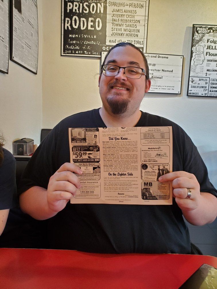 A man is holding a pamphlet in front of a sign that says prison rodeo