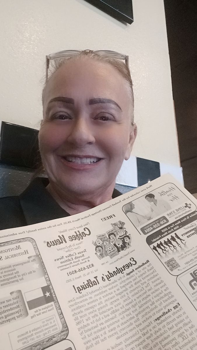 Woman smiling, holding newspaper, in a diner setting.