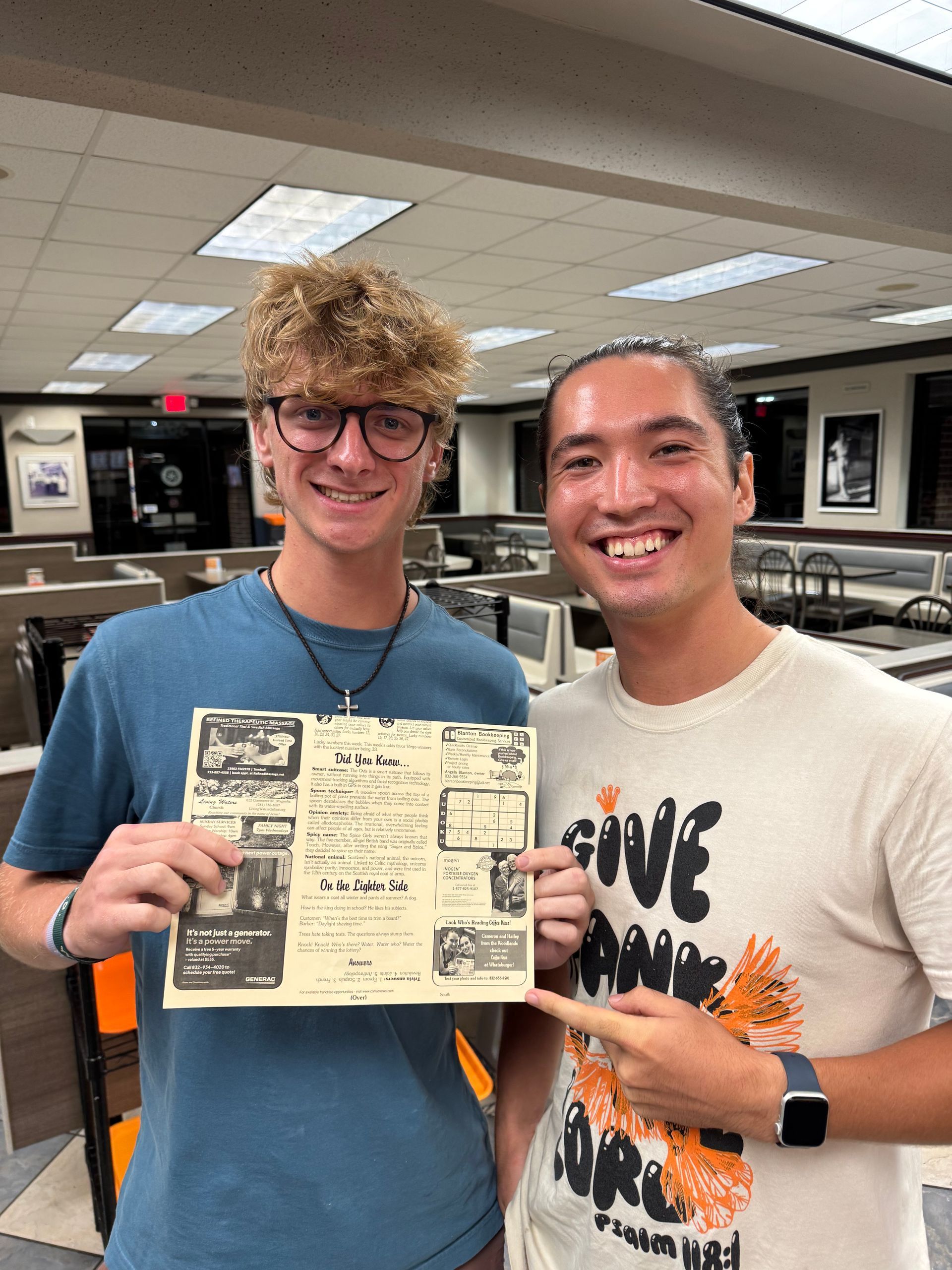 Two people holding and pointing at a printed paper with text and images; indoor setting.