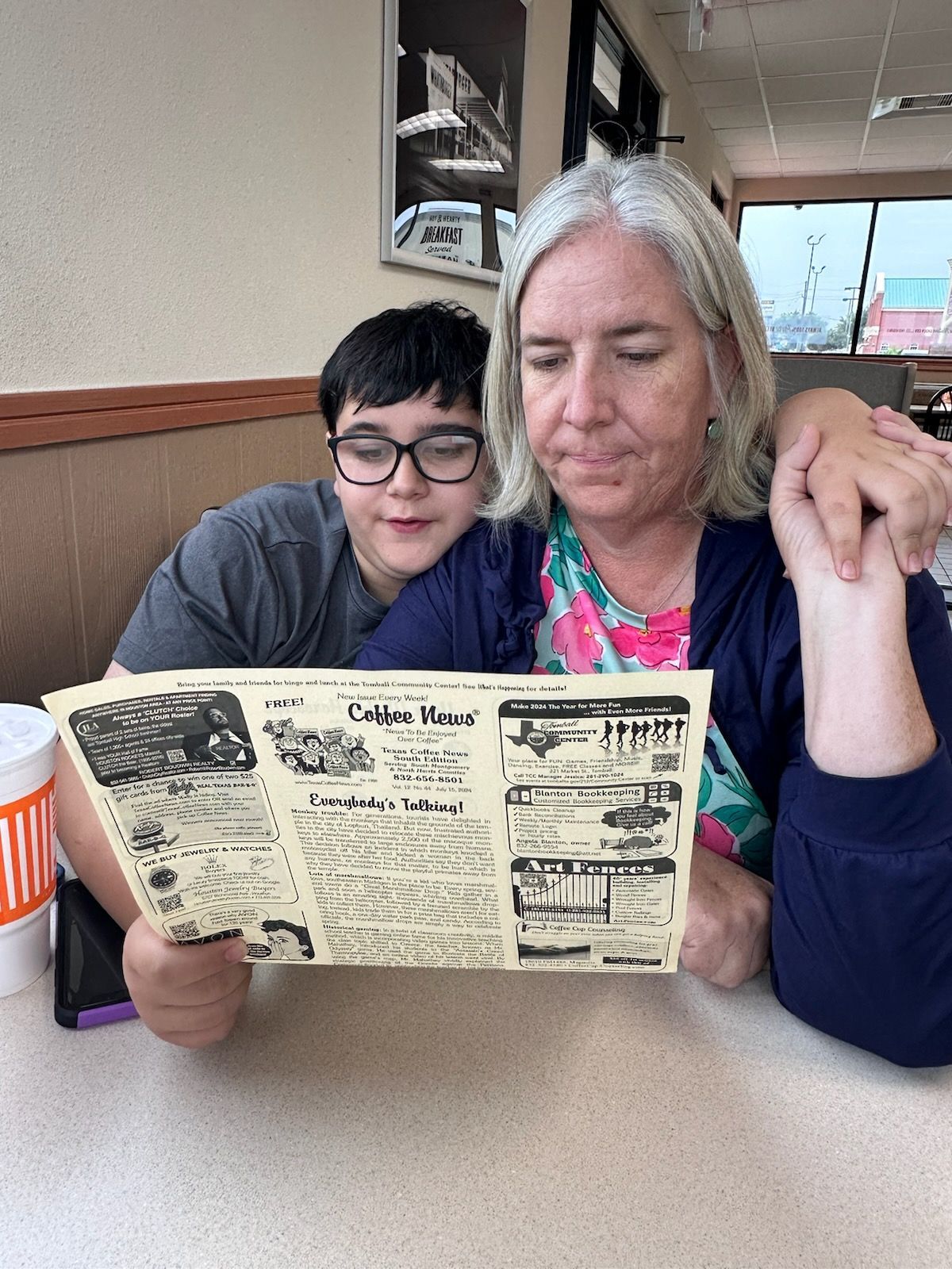 Person with gray hair and person with glasses looking at a paper in a restaurant. 