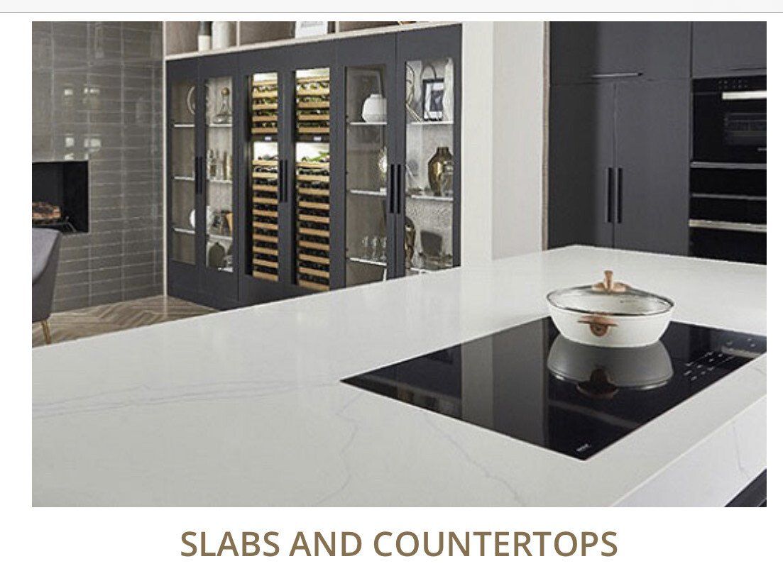 Modern kitchen with white countertops and built-in stovetop. Wine storage visible in background.