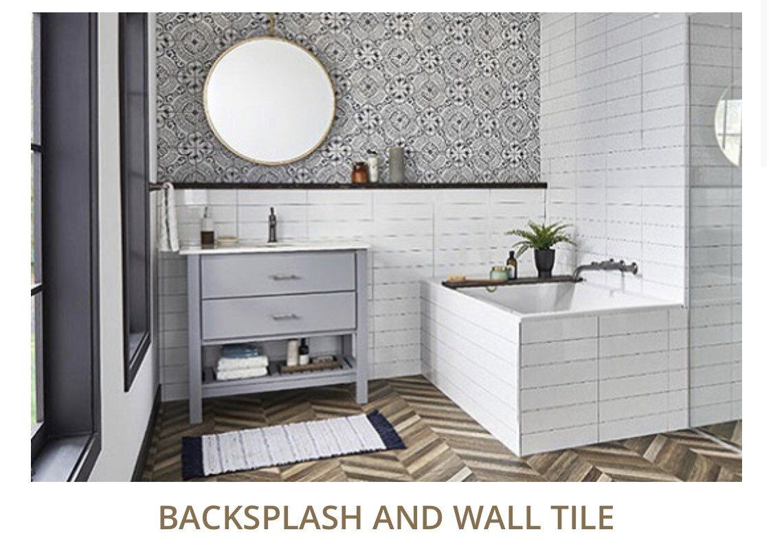 Bathroom with patterned backsplash, white wall tile, gray vanity, round mirror, and a bathtub.