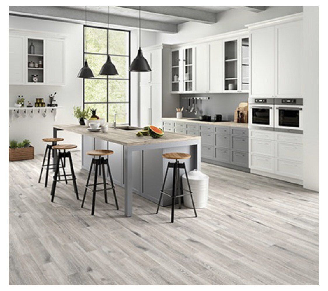 Modern kitchen with white cabinets, gray island, and wood-look flooring.