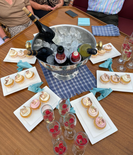 Een feestelijke tafelsetting met een metalen emmer wijn en champagne, omringd door schalen met cupcakes en gevulde glazen.