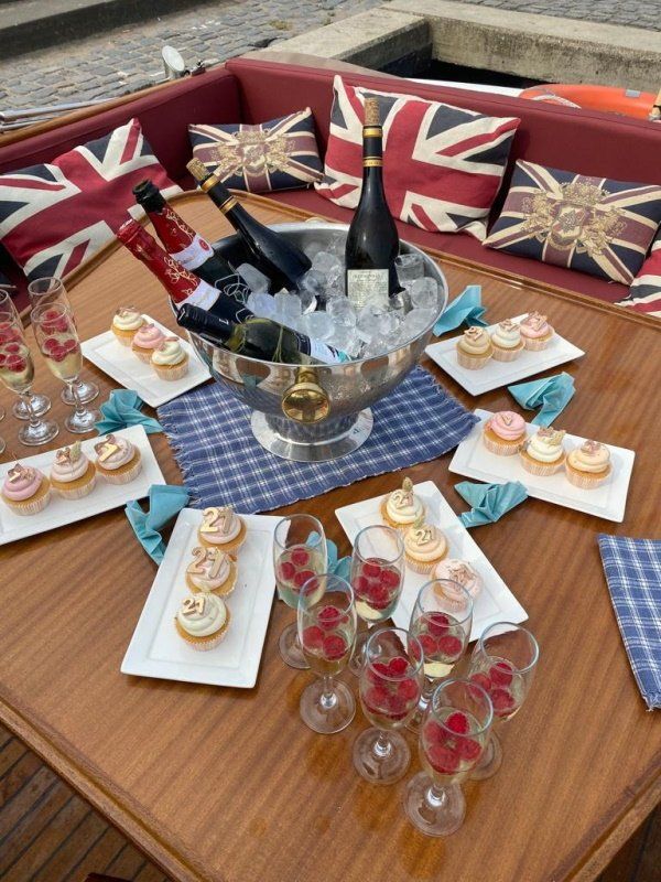 Op een houten tafel op een boot staan ​​wijn in een zilveren ijsemmer, champagneglazen met frambozen en schalen met cupcakes.