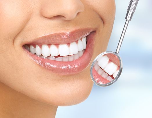 A Woman Is Smiling While Having Her Teeth Examined by A Dentist — Cane to Coast Dentures in Sarina, QLD