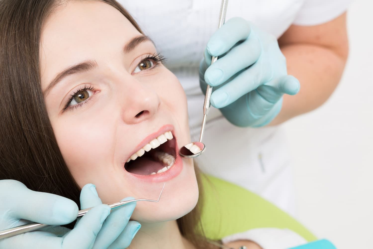 A Woman Is Getting Her Teeth Examined by A Dentist — Cane to Coast Dentures in Moranbah, QLD