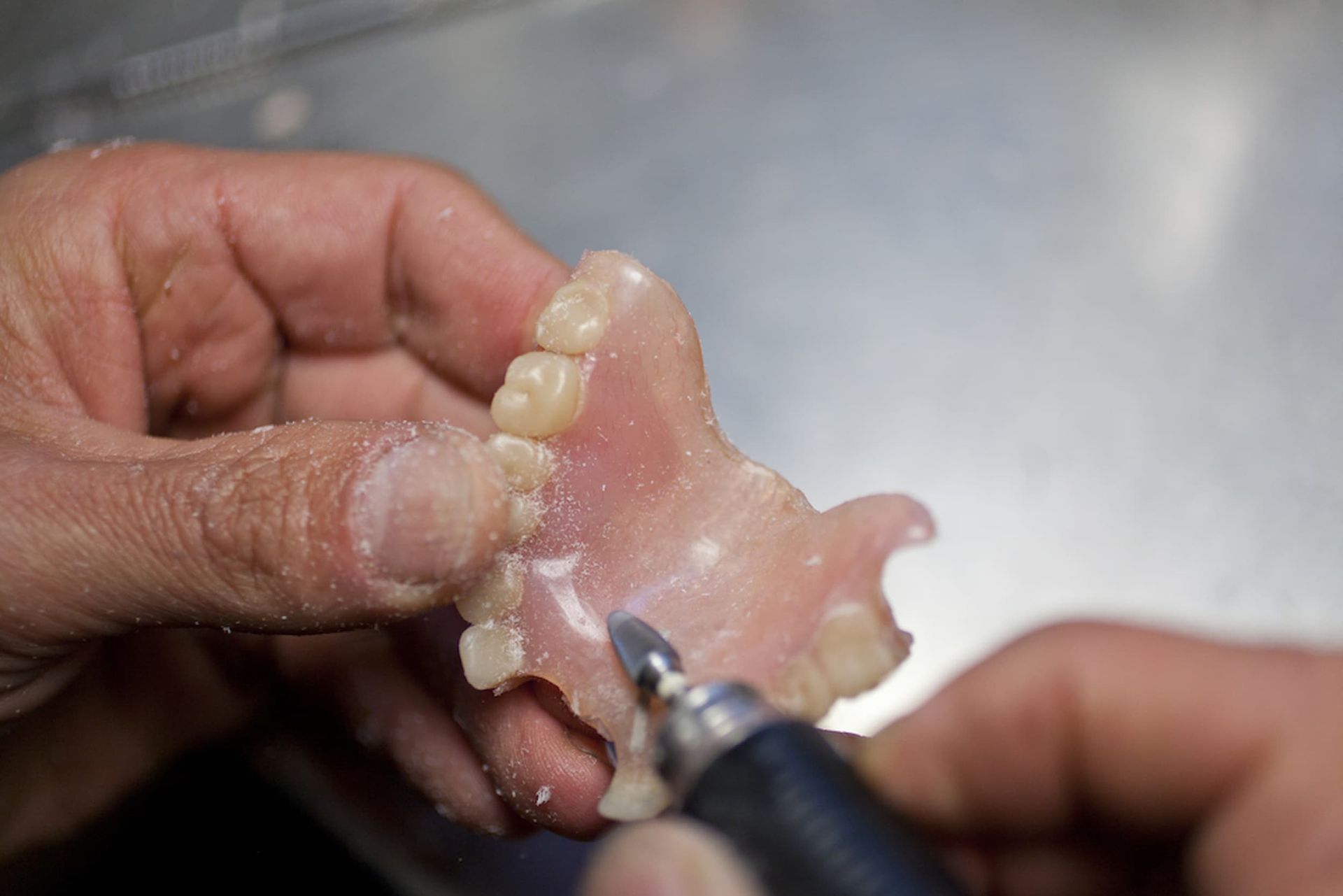 A Person Is Grinding a Denture with A Machine — Cane to Coast Dentures in Sarina, QLD