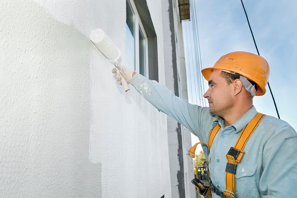 A man is painting a wall with a roller.