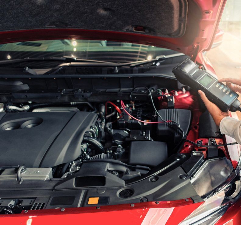 Mechanic Holding A Digital Multimeter Testing Battery — Mechanic In Noosaville, QLD
