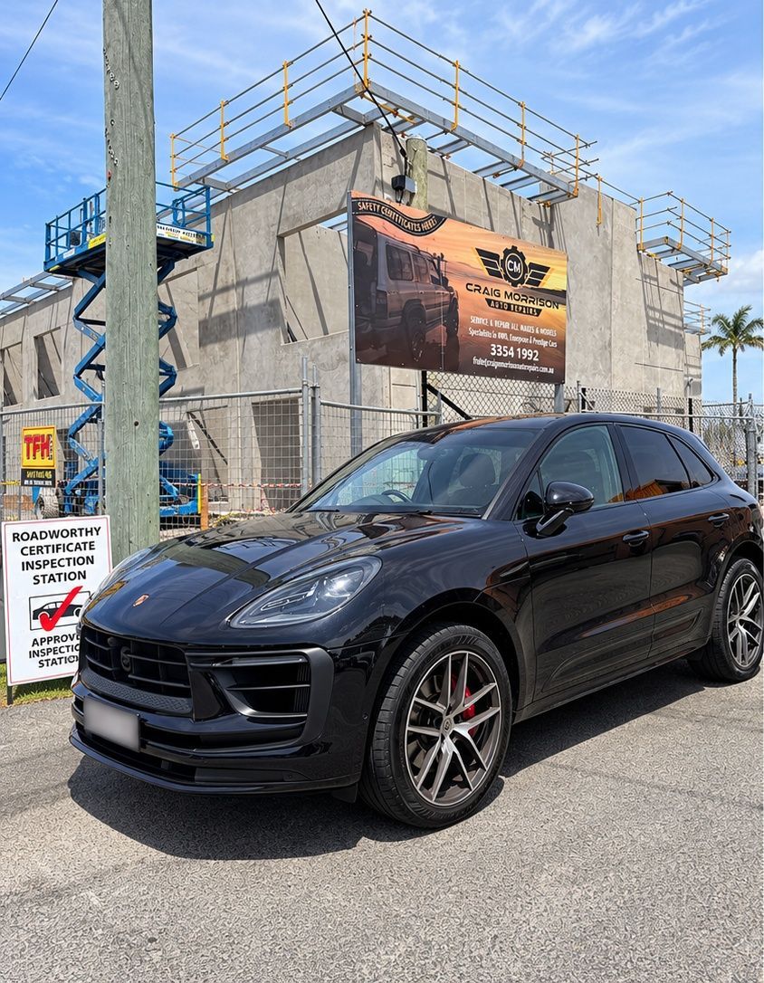 Black SUV parked on a street beside a concrete building under construction, with scaffolding and a banner. — Mechanic In Noosaville, QLD