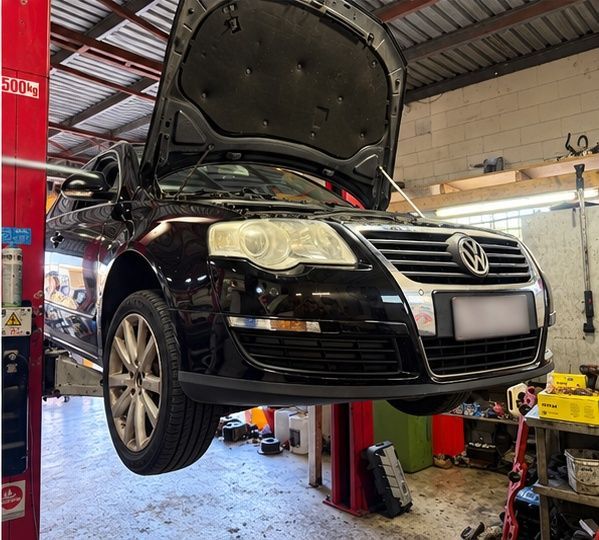 Black Volkswagen sedan lifted in auto shop with hood open for repair — Mechanic In Noosaville, QLD