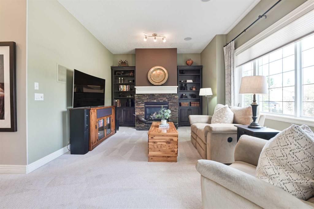 Bright living room with beige sofa, fireplace, wall-mounted TV, and large window.
