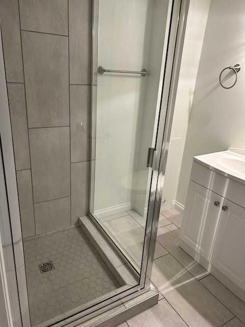 Modern tiled bathroom with a glass walk-in shower and vanity sink.