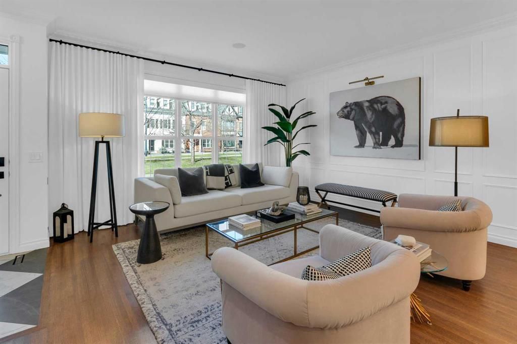 Modern living room with beige chairs, a sofa, floor lamps, and a large elephant artwork by a window