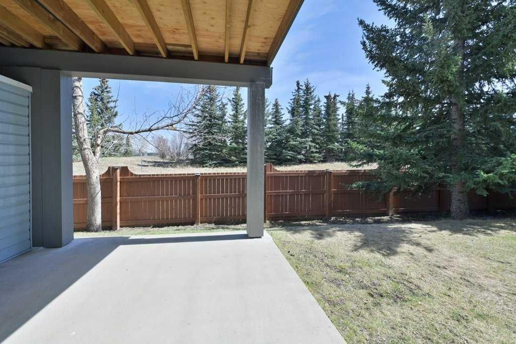 Covered patio with concrete floor overlooking a fenced backyard and trees