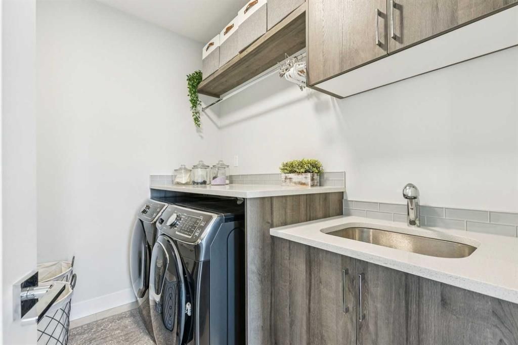 Compact laundry room with washer and dryer, wood cabinets, and a small sink
