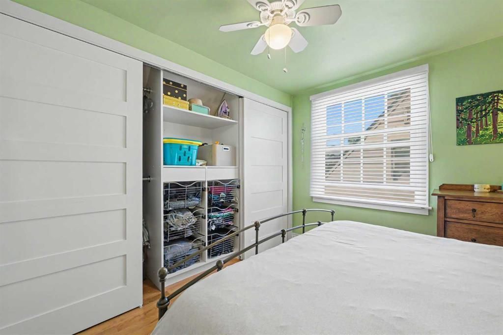 Bright green bedroom with white bed, open closet, and window letting in daylight