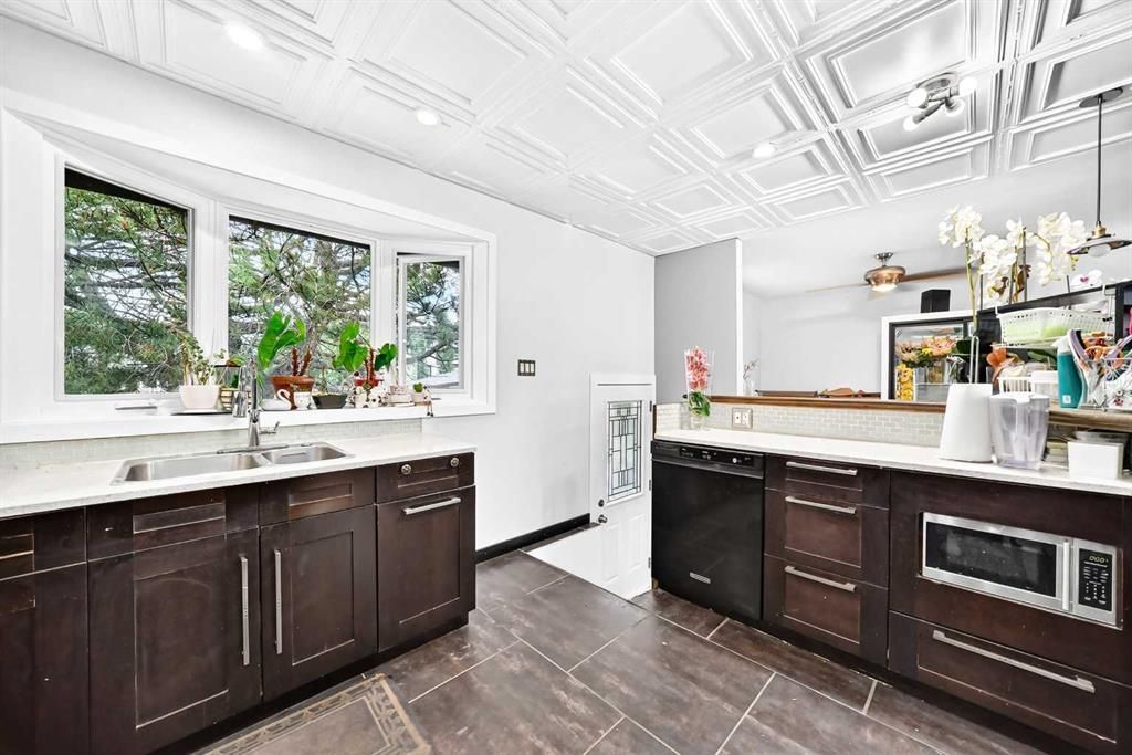 Bright modern kitchen with white ceiling, dark cabinets, large windows, and a sink-side countertop