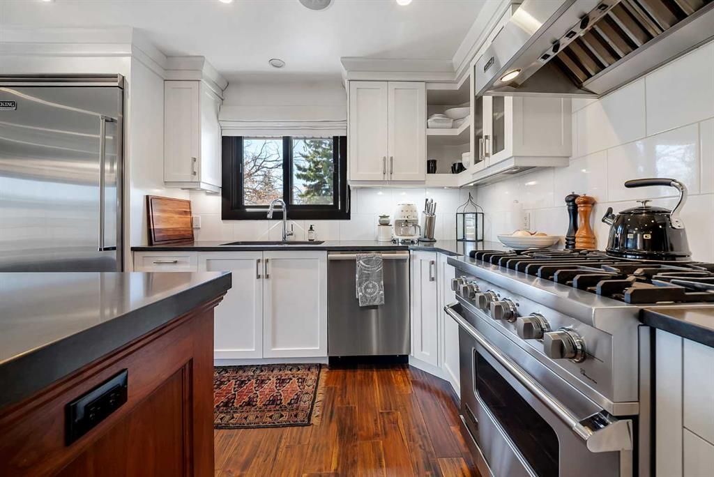 Modern kitchen with stainless steel appliances, white cabinets, and a black window over the sink.