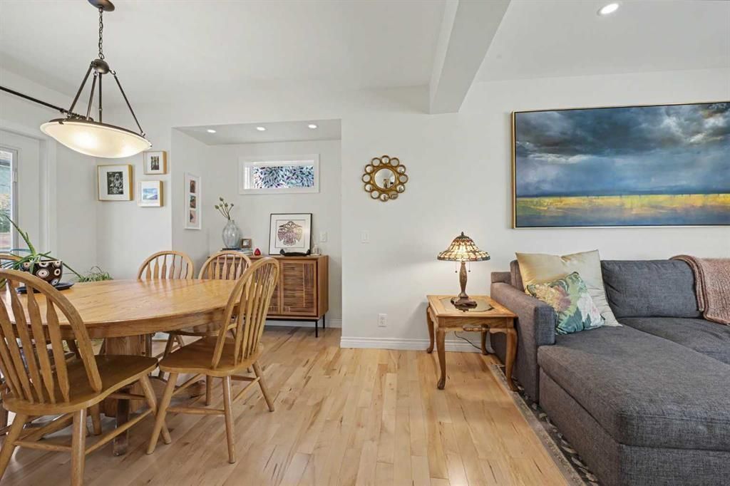 Bright open-concept living room and dining area with wood floors, gray sofa, and seaside wall art
