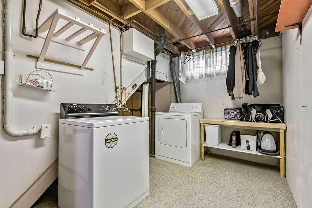 Laundry room with washer, drying rack, and hanging clothes under exposed beams
