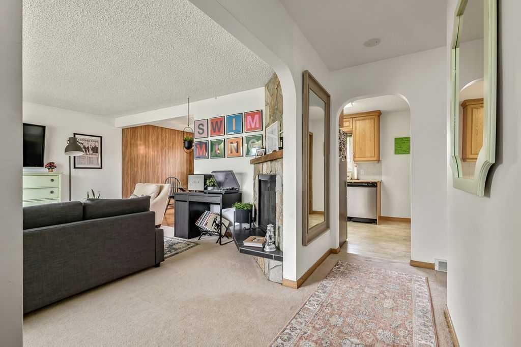Bright living room and hallway with gray sofa, colorful wall art, and patterned rug