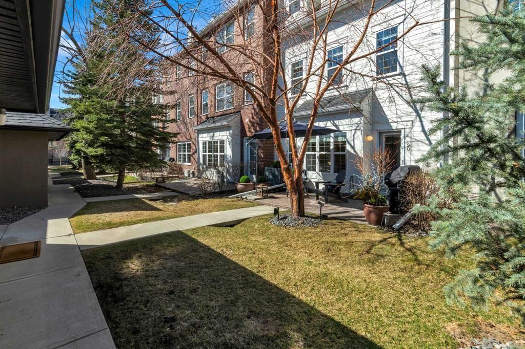 Apartment courtyard with trees, grass, and sliding glass doors along a brick and stucco building.