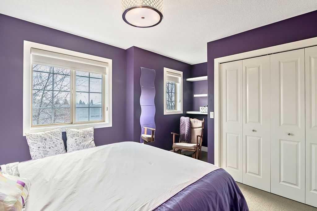 Purple bedroom with white bed, window, dresser, and closet doors