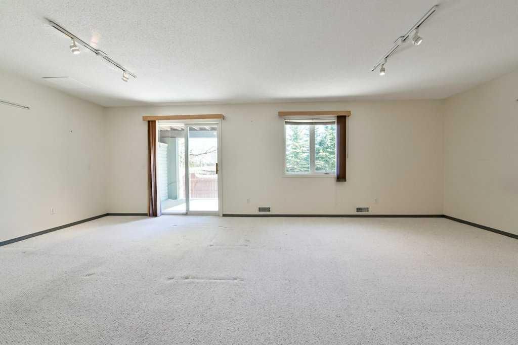 Empty white living room with carpet, sliding glass door, and two windows