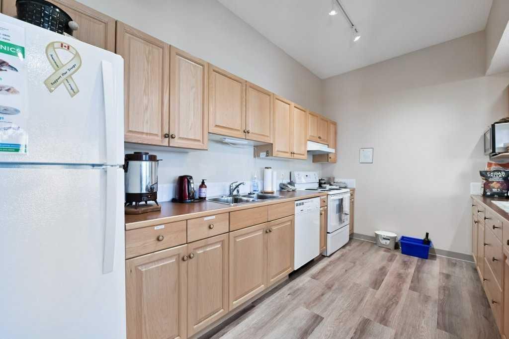 Bright kitchen with light wood cabinets, white appliances, and hardwood floors