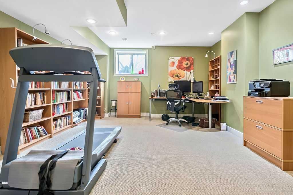 Bright exercise room with treadmill, office chair, desk, cabinets, and soft green walls