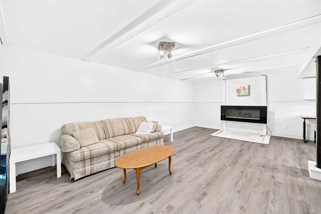 Bright living room with striped sofa, wooden coffee table, fireplace, and gray wood flooring