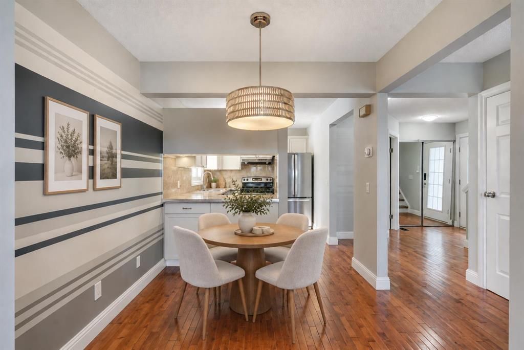 Bright dining room with striped gray walls, round table, white chairs, and hardwood floors.