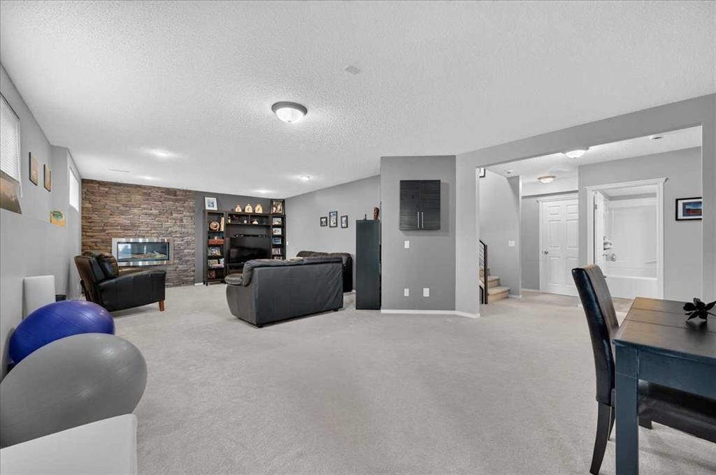Spacious finished basement living room with gray sectional, brick fireplace, pool table, and dining area