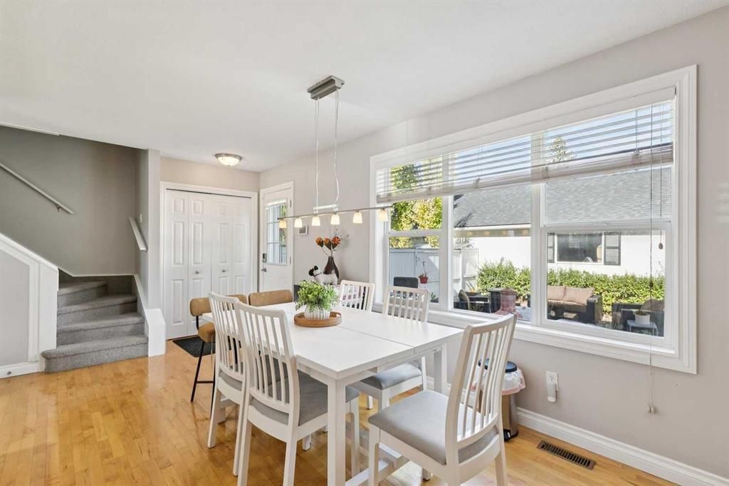 Bright dining room with white table and chairs, large windows, and light wood floors