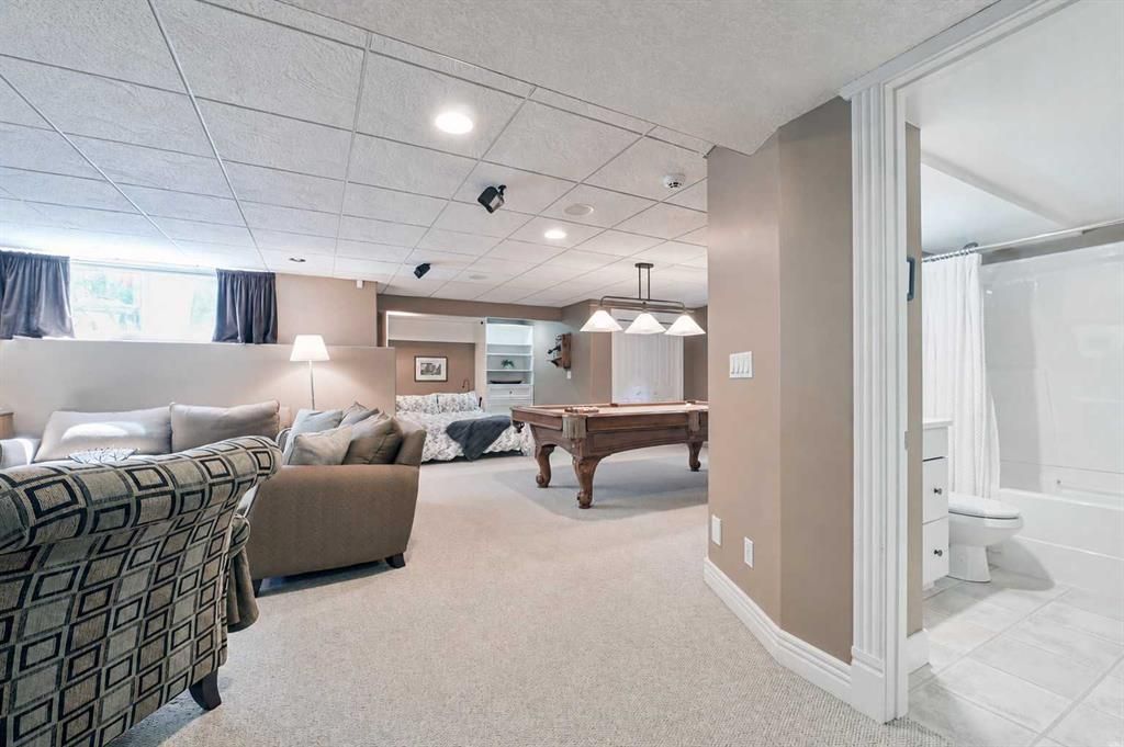 Cozy basement living room with sectional sofa, pool table, and adjacent bathroom doorway