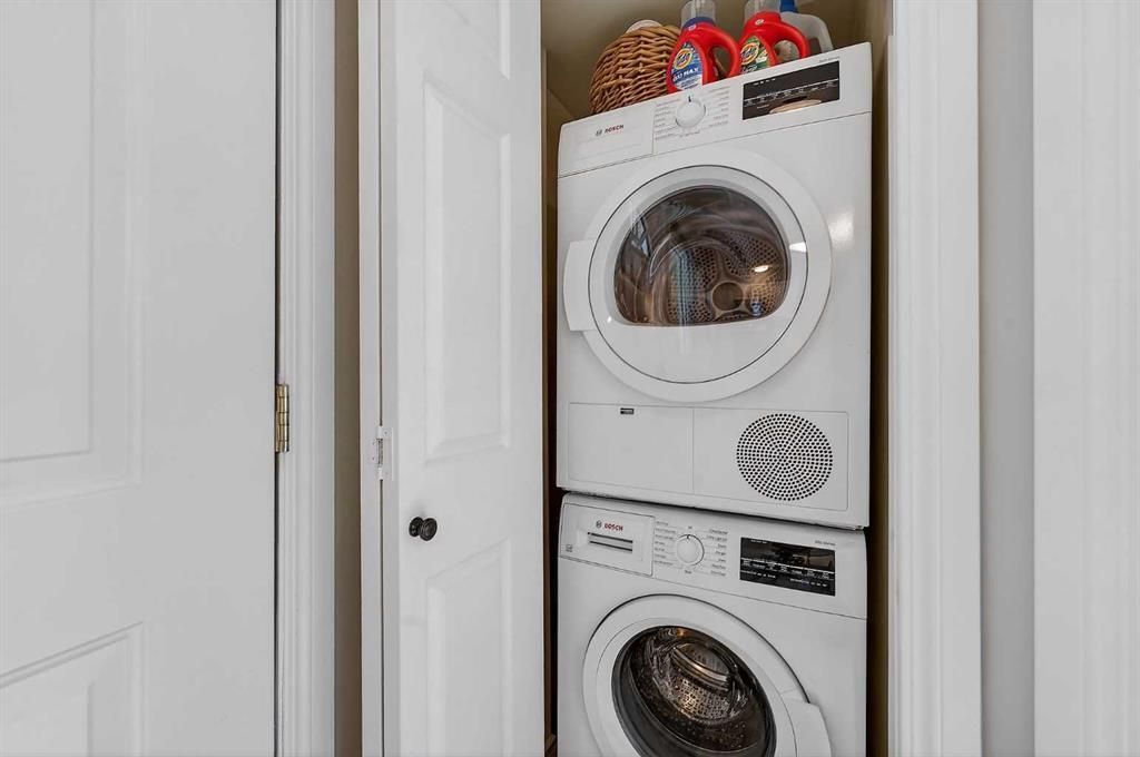 Stacked washer and dryer in a narrow closet, with laundry baskets on top.