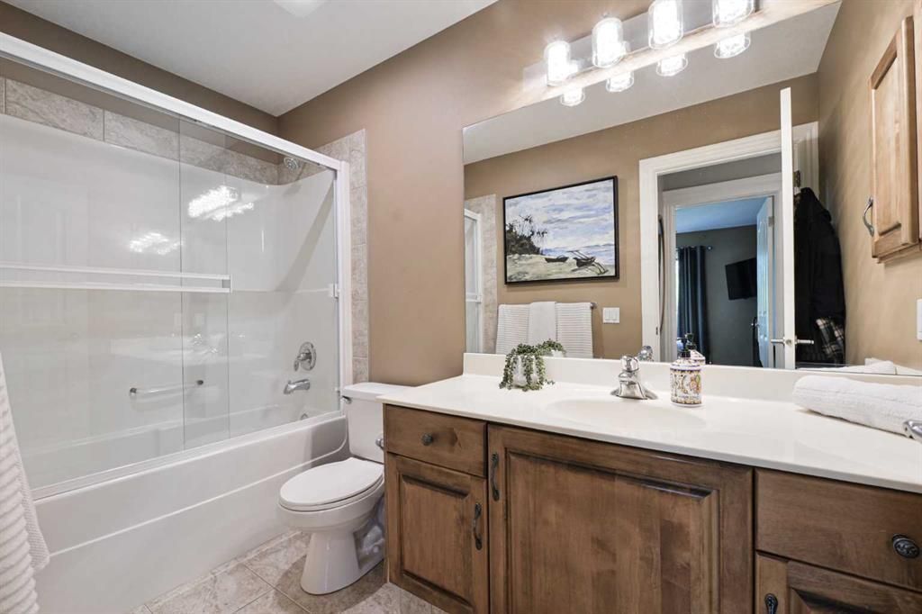 Bright bathroom with white tub, glass shower, wood vanity, large mirror, and light beige walls
