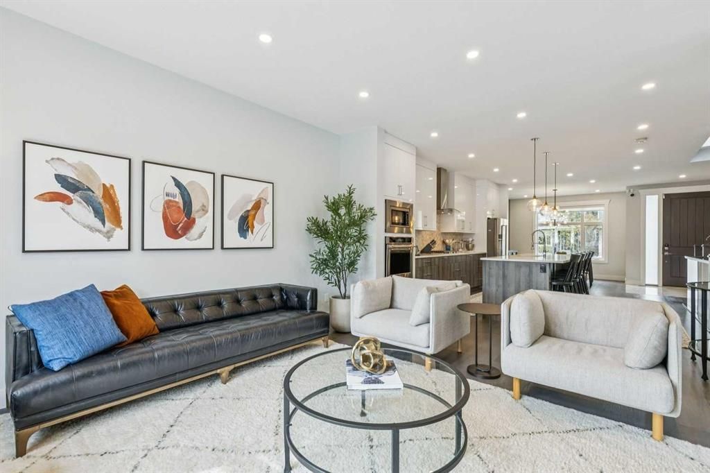 Bright modern living room with black and beige sofas, glass coffee table, and framed wall art
