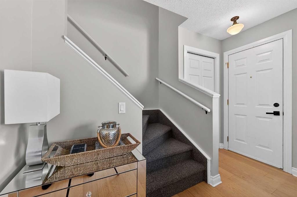 Staircase foyer with gray walls, white doors, a small table, and light wood flooring