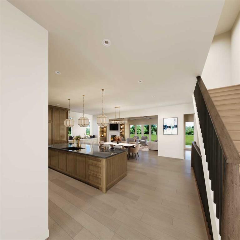 Modern open-plan kitchen and dining area with wood island, pendant lights, staircase, and large windows