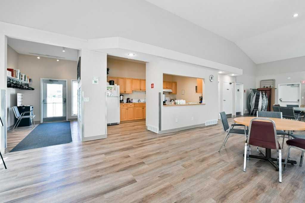 Open-plan living area with wood floors, kitchen pass-through, and dining table near large windows.