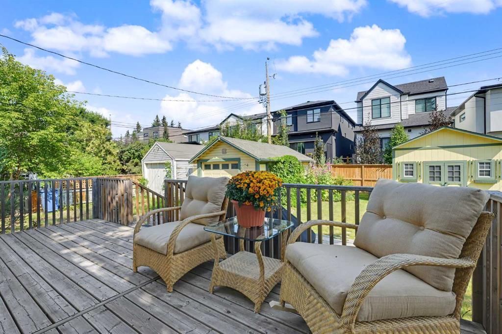 Deck with wicker chairs and potted flowers overlooking colorful houses under a blue sky