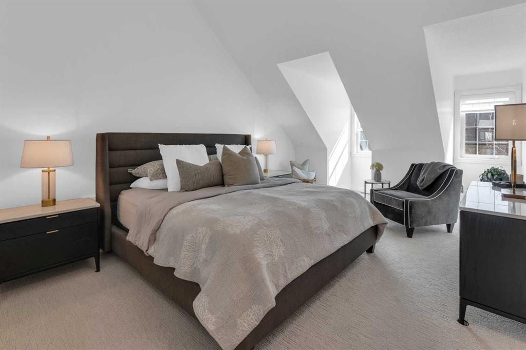 Modern bedroom with a large bed, dark furniture, and gray accents in a bright attic-style room